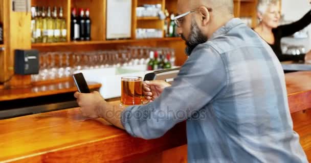 男子在酒吧4K 柜台喝啤酒时使用手机 — 图库视频影像