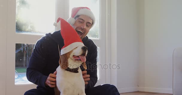 Sonriente Joven Poniendo Santa Gorra Perro Mascota Casa — Vídeo de stock