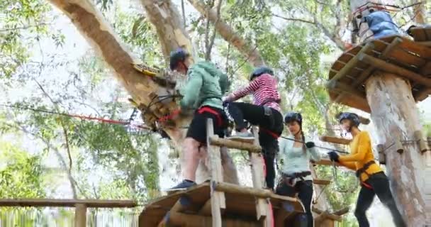 男子协助妇女在森林的拉链线上固定安全带4K — 图库视频影像