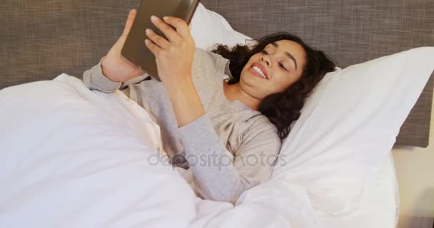 女人躺在床上使用她的片剂在卧室里4K — 图库视频影像