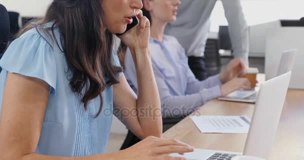 女性エグゼクティブ オフィス でノート パソコンを使用しながら携帯電話で話しています — ストック動画