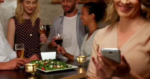 Frau Benutzt Ihr Handy Während Freunde Hintergrund Der Bar Interagieren — Stockvideo