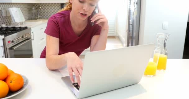 Mulher Bonita Falando Telefone Celular Enquanto Usa Laptop Cozinha — Vídeo de Stock