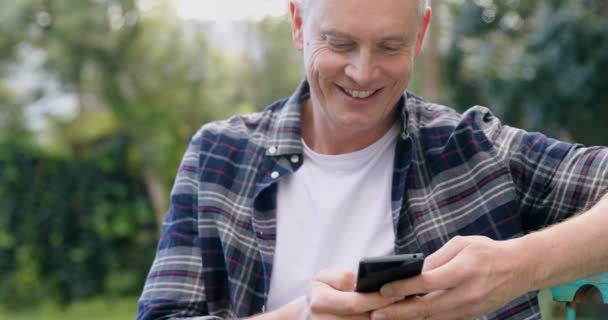 成熟した男の庭 で携帯電話を使う — ストック動画