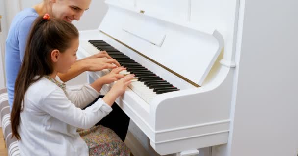 Mother Assisting Daughter Playing Piano Home — Stock Video