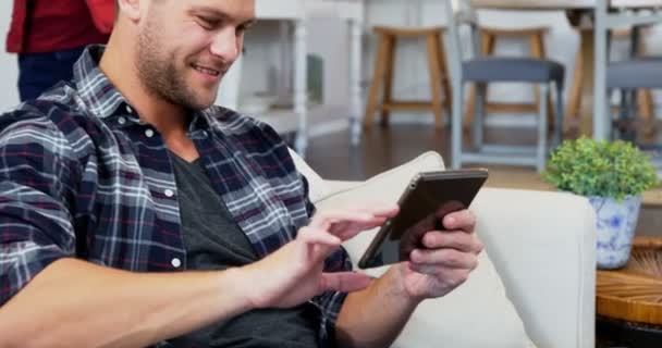 Ευτυχισμένο Ζευγάρι Χρησιμοποιώντας Ψηφιακό Tablet Πίνοντας Καφέ Στο Σαλόνι — Αρχείο Βίντεο