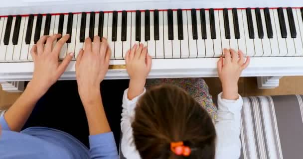 Mother Assisting Daughter Playing Piano Home — Stock Video