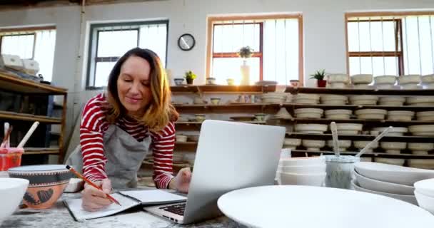 Female Potter Checking Orders Laptop Pottery Worktop — Stock Video