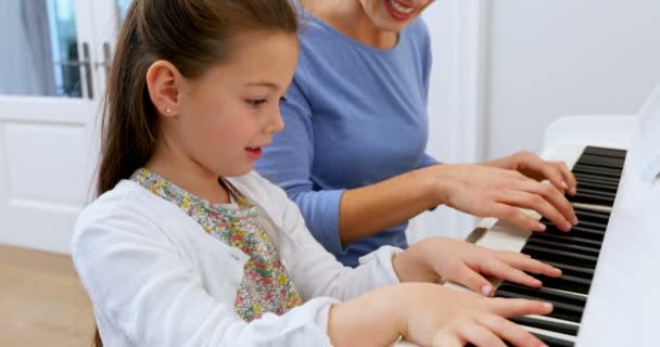 Mother Assisting Daughter Playing Piano Home — Stock Video