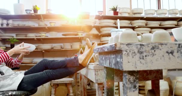 Töpferin Checkt Schale Beim Entspannen Auf Stuhl Töpferwerkstatt — Stockvideo