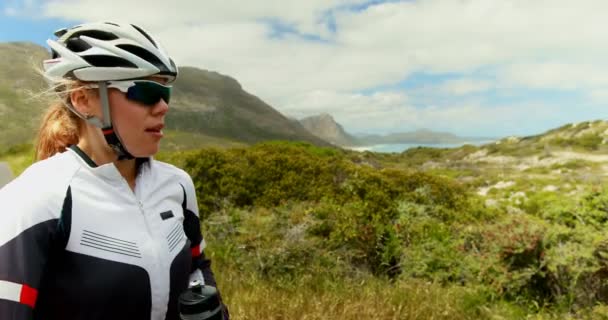 若い女性サイクリスト田舎道 で水を飲む — ストック動画