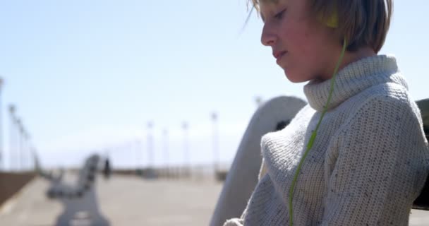 一个阳光明媚的日子 在海滩上听音乐的女孩在沙滩上的耳机4K — 图库视频影像