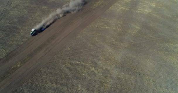 の晴れた日に収穫されたフィールド上を移動するトラクターの航空写真 — ストック動画