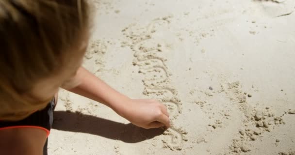 Κορίτσι Γραφής Του Ονόματος Στην Άμμο Στην Παραλία Μια Ηλιόλουστη — Αρχείο Βίντεο