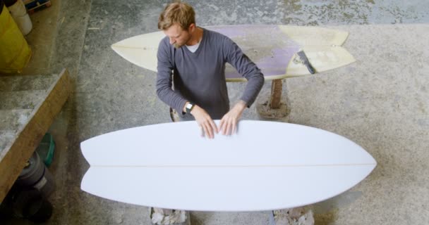 Άνθρωπος Που Εξετάζει Μια Σανίδα Του Surf Στο Εργαστήριο — Αρχείο Βίντεο