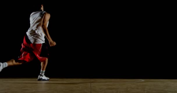 黒背景 に対して裁判所で遊んでの男子バスケット ボール選手 — ストック動画