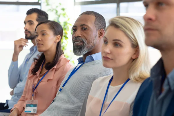 ビジネスカンファレンスで聴衆の列に座っているビジネスクリエイターの多様なグループの側面図 — ストック写真