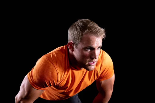 一个身穿运动服的白人肌肉发达的男子前视近视 身体前倾 锻炼后恢复 在黑色背景上 — 图库照片