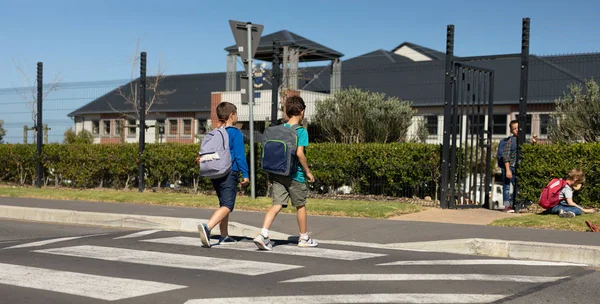 Vue Arrière Deux Écoliers Caucasiens Portant Des Sacs Dos Traversant — Photo