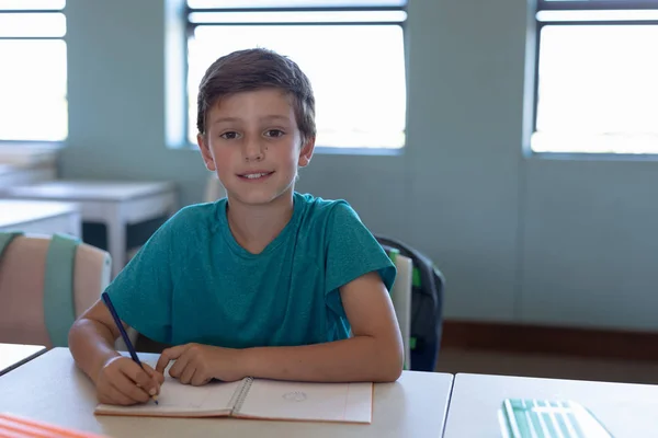 Portrait Caucasian Schoolboy Wearing Blue Shirt Sitting Desk Writing Notebook — 스톡 사진