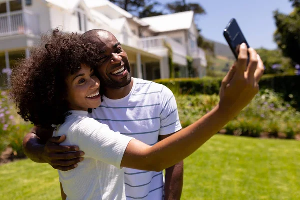 Bahçede Dikilen Kucaklaşan Akıllı Telefonuyla Selfie Çeken Melez Bir Çiftin — Stok fotoğraf