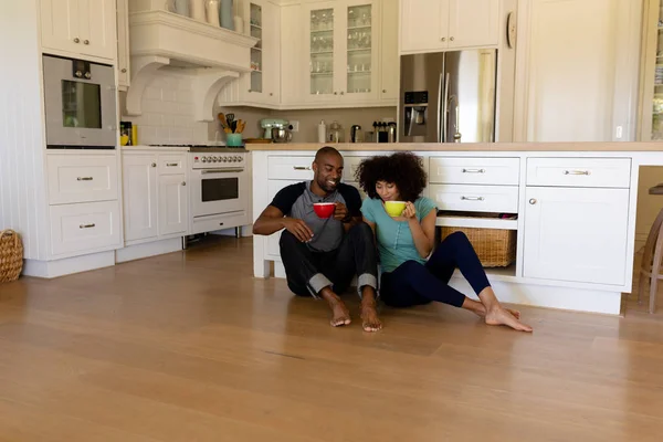 Front View Mixed Race Couple Sitting Floor Kitchen Holding Cups — Stock Photo, Image