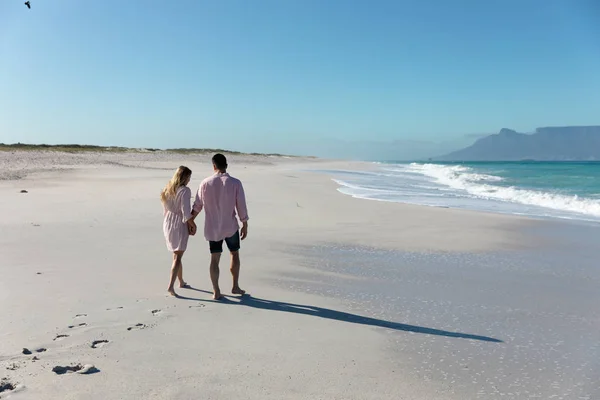 一对白种人夫妇在海滩上的背影 背景是蓝天和大海 他们手牵手散步 — 图库照片