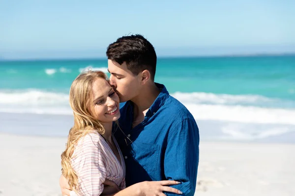 背景に青い空と海とビーチに立っている白人のカップルのフロントビュー 抱擁とキス — ストック写真