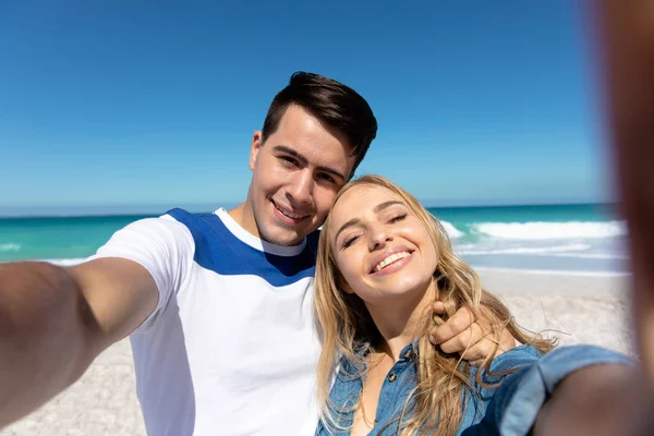 一对白种人夫妇站在海滩上 背景是蓝天和大海 拥抱并自拍的前景 — 图库照片