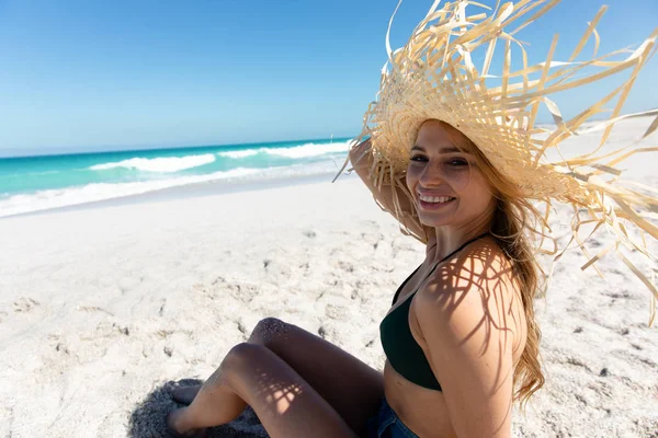 白人女性が麦藁帽子をかぶって 青い空と海を背景にビーチに寝転がり 日光浴 — ストック写真
