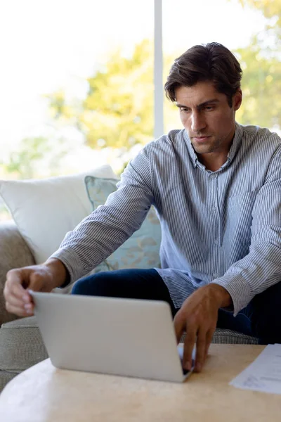 自宅の白人男性のフロントビューを閉じる ノートパソコンを使用してソファの上のリビングルームに座って — ストック写真