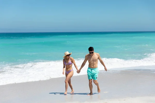青い空と海を背に海岸を歩いている白人夫婦の正面ビュー 手を取り合って笑顔 — ストック写真