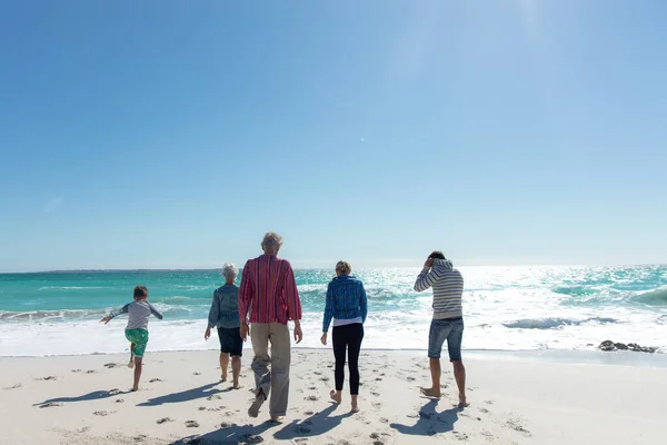 背景是蓝天蓝海的沙滩上一代代白人家庭的后视镜 他们走向大海 放松身心 — 图库照片