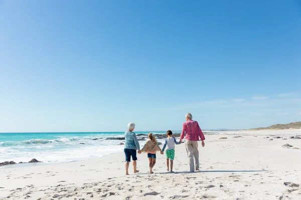 后视镜遥不可及的几代白人家庭在沙滩上 背景蓝天蓝海 手牵手散步 — 图库照片