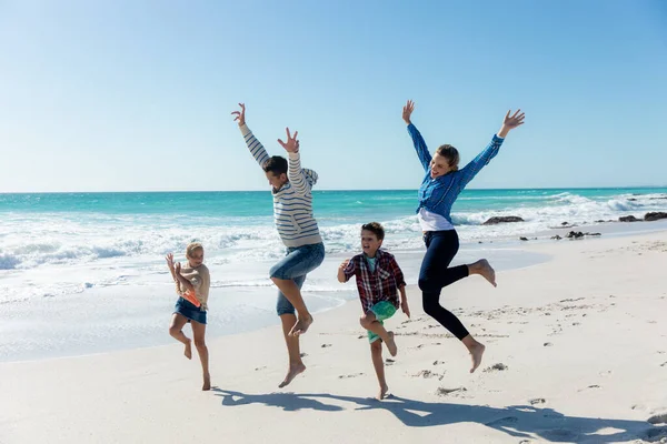 在背景是蓝天蓝海的海滩上 一个白人家庭的正面景象 他们一边走路 一边举手 一边玩乐 — 图库照片