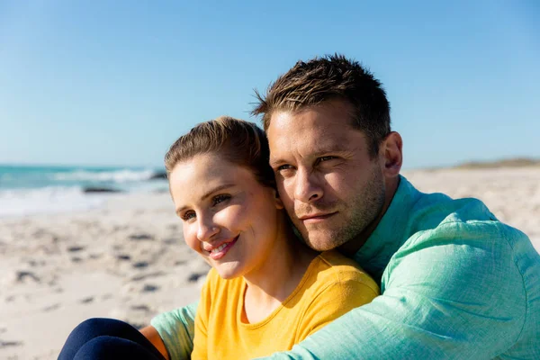 一对白种人夫妇斜倚在海滩上 背景是蓝天和大海 拥抱着他们 望向远方 — 图库照片