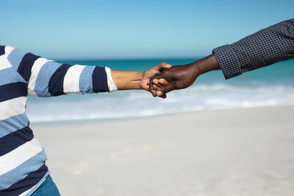 两口子手牵手站在沙滩上 蓝天为背景的侧视图 — 图库照片