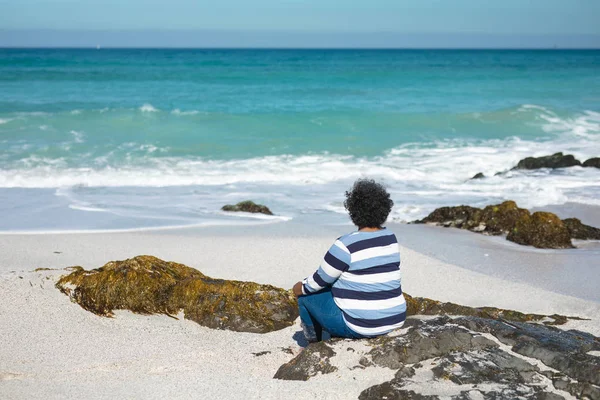 Baksidan Senior Afroamerikansk Kvinna Sitter Klippa Stranden Med Blå Himmel — Stockfoto