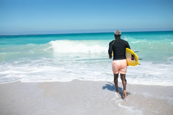 Bakifrån Senior Afroamerikansk Man Strand Solen Bär Surfbräda Armen Och — Stockfoto