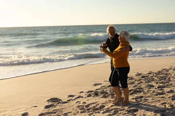 Side View Senior Caucasian Couple Beach Wearing Sweaters Embracing Dancing — 스톡 사진