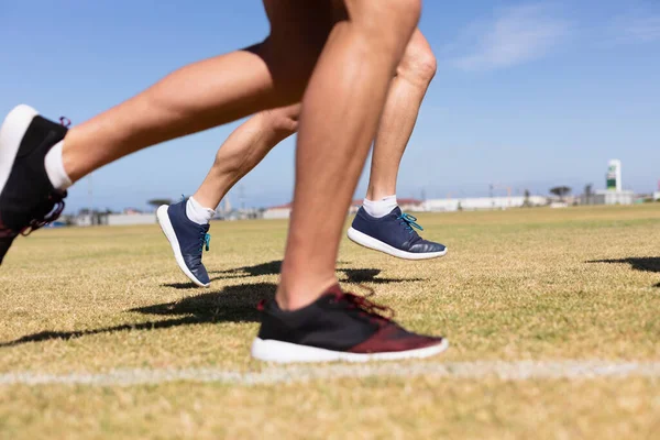 两名男子跑步者在运动场训练 在阳光下在草地跑道上跑步时双腿的低段侧视图 — 图库照片