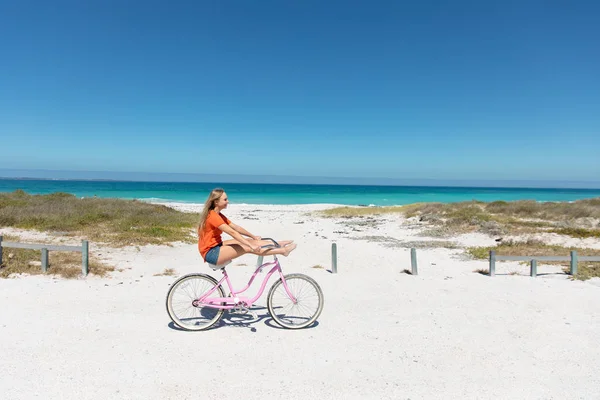 一个背景是蓝天蓝海的白人女人的侧视图 骑自行车 周末海滩度假 生活方式和休闲 — 图库照片