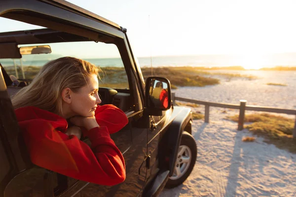 一个白人女人在一辆敞着的顶层汽车里从窗户往外看的侧视图 周末海滩度假 生活方式和休闲 — 图库照片