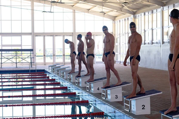 Widok Boku Wieloetnicznej Grupy Męskich Pływaków Basenie Stojących Blokach Startowych — Zdjęcie stockowe