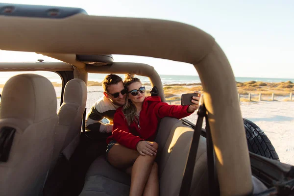 オープントップカー内の白人カップルのフロントビュー 笑顔と自撮り 週末のビーチ休暇 ライフスタイルとレジャー — ストック写真