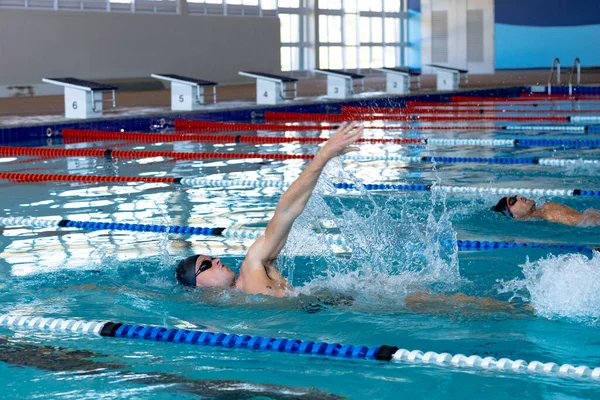 水泳プールで2人の白人男性の水泳選手のサイドビューでは レーンで互いに競争し 背泳ぎ 競技のために一生懸命練習する水泳選手 — ストック写真