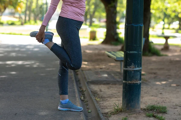 侧视在公园里锻炼的妇女的低部分 在锻炼前在路灯旁伸展 — 图库照片
