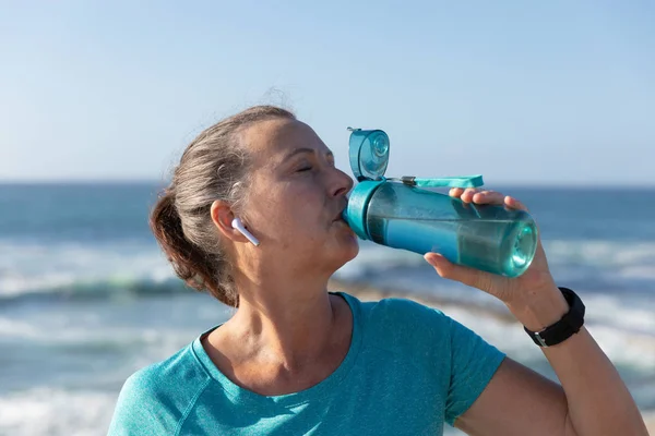 晴れた日に遊歩道で働く成熟した中年の白人女性の側面図 飲料水 — ストック写真