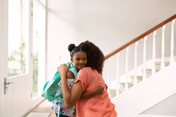 一位非洲裔美国妇女和她的女儿在离家上学前在走廊拥抱的侧视图 — 图库照片