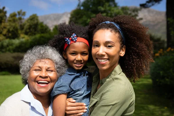 一个微笑的非洲裔美国祖母与她的成年女儿和孙女抱在母亲身边 对着相机笑的画像 家庭享受家庭生活 生活方式概念 — 图库照片